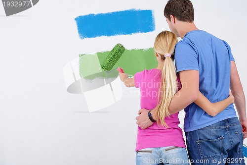 Image of happy couple paint wall at new home