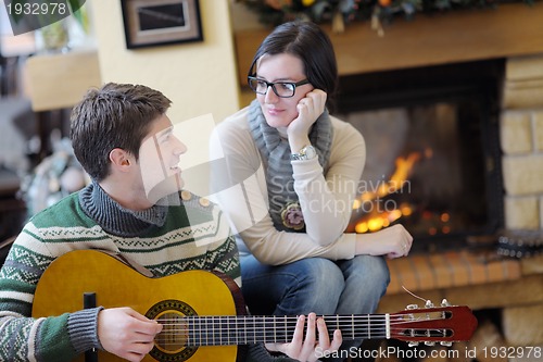 Image of Young romantic couple sitting and relaxing in front of fireplace
