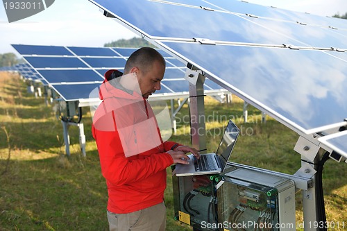 Image of engineer using laptop at solar panels plant field