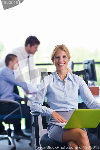 Image of business woman with her staff in background at office