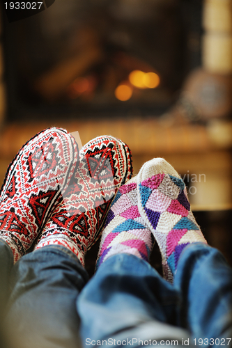 Image of Young romantic couple sitting on sofa in front of fireplace at h