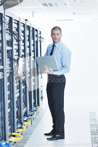 Image of businessman with laptop in network server room