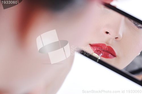 Image of beautiful young woman applying makeup