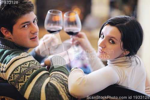 Image of Young romantic couple sitting and relaxing in front of fireplace