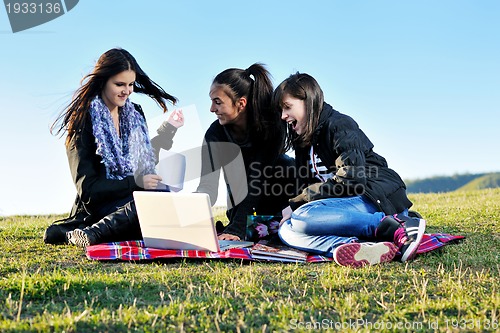 Image of group of teens working on laptop outdoor