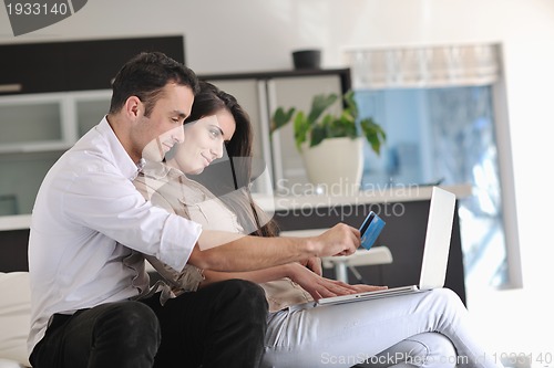 Image of joyful couple relax and work on laptop computer at modern home