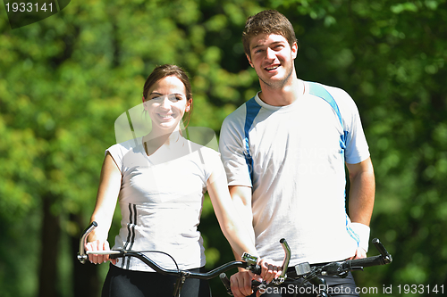 Image of Happy couple riding bicycle outdoors