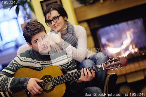 Image of Young romantic couple relax on sofa in front of fireplace at hom