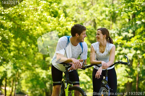 Image of Happy couple riding bicycle outdoors