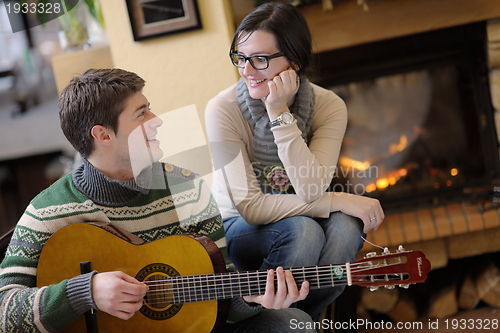 Image of Young romantic couple sitting on sofa in front of fireplace at h