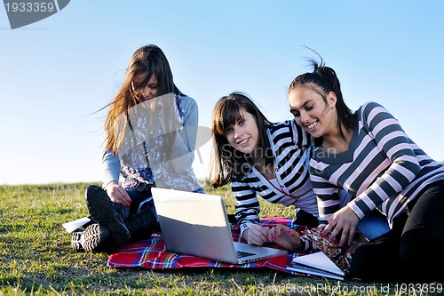 Image of group of teens working on laptop outdoor