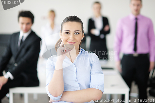 Image of business woman standing with her staff in background
