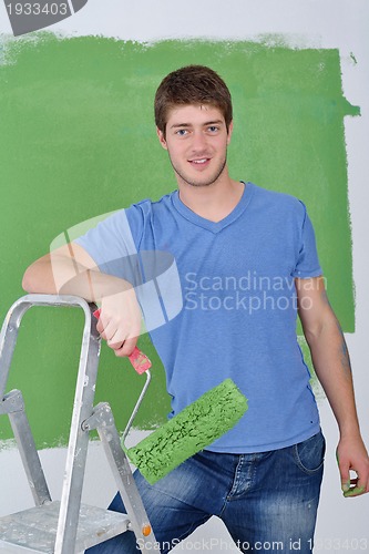 Image of handsome young man paint white wall in color