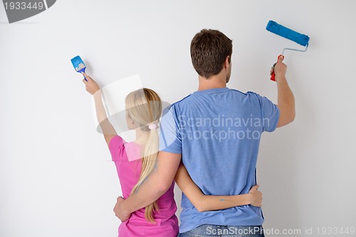 Image of happy couple paint wall at new home