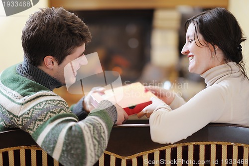 Image of Young romantic couple sitting and relaxing in front of fireplace