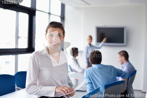 Image of business woman with her staff in background at office