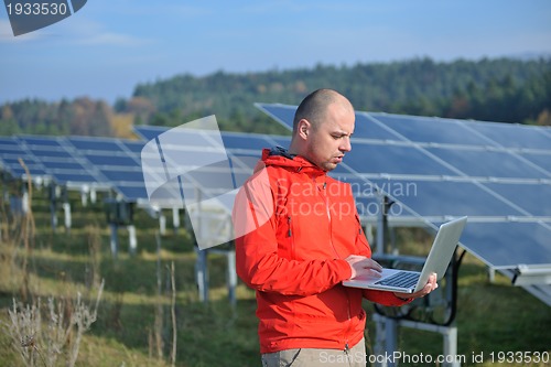 Image of engineer using laptop at solar panels plant field