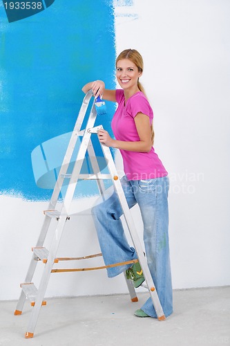 Image of happy smiling woman painting interior of house