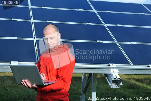 Image of engineer using laptop at solar panels plant field