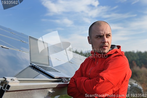 Image of engineer using laptop at solar panels plant field