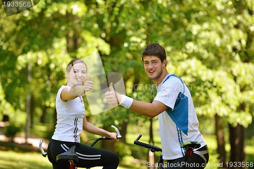 Image of Happy couple riding bicycle outdoors