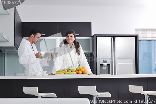 Image of Happy couple reading the newspaper in the kitchen at breakfast