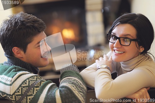Image of Young romantic couple sitting and relaxing in front of fireplace