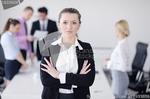 Image of business woman standing with her staff in background