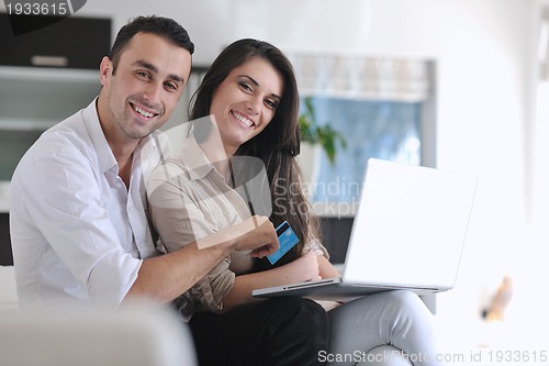 Image of joyful couple relax and work on laptop computer at modern home
