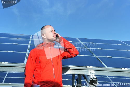 Image of engineer using laptop at solar panels plant field