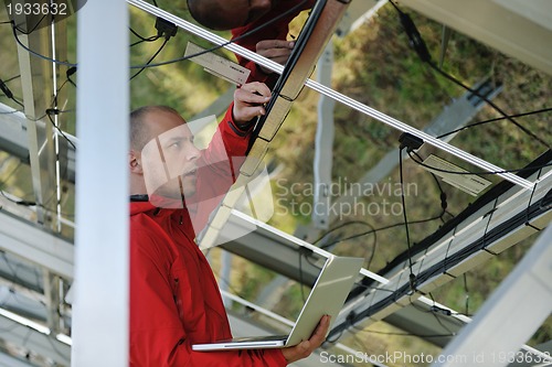 Image of engineer using laptop at solar panels plant field