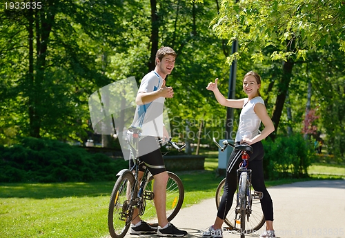 Image of Happy couple riding bicycle outdoors