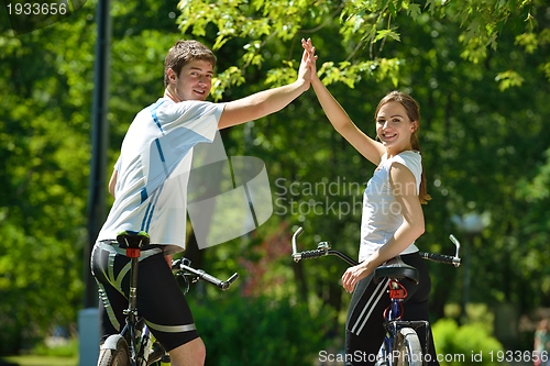 Image of Happy couple riding bicycle outdoors