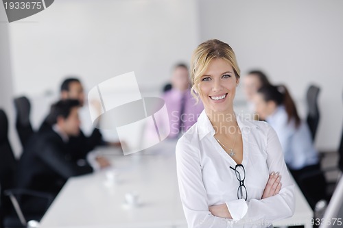 Image of business woman standing with her staff in background
