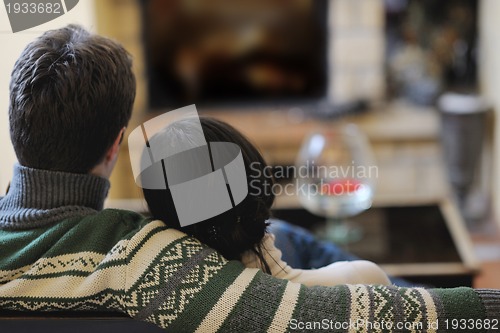 Image of Young romantic couple sitting and relaxing in front of fireplace