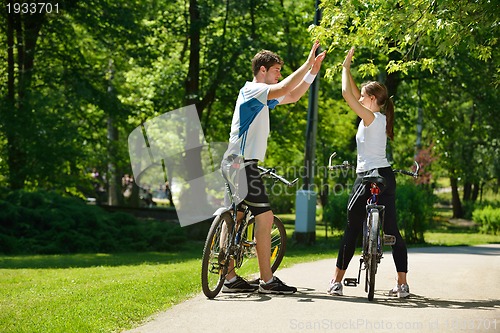 Image of Happy couple riding bicycle outdoors