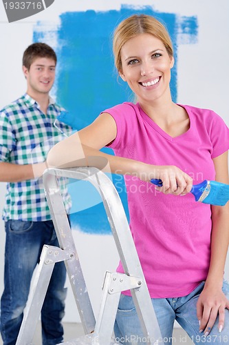 Image of happy couple paint wall at new home