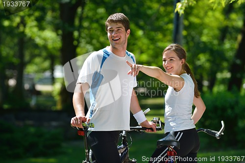 Image of Happy couple riding bicycle outdoors