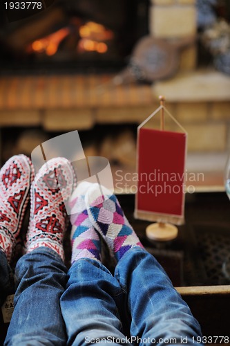 Image of Young romantic couple sitting and relaxing in front of fireplace