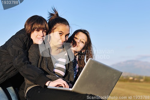 Image of group of teens working on laptop outdoor