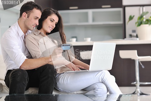 Image of joyful couple relax and work on laptop computer at modern home