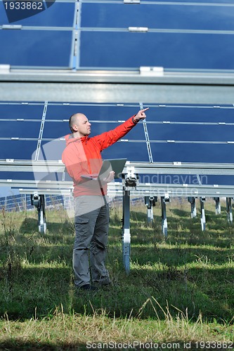 Image of engineer using laptop at solar panels plant field