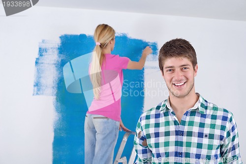 Image of happy couple paint wall at new home