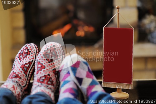 Image of Young romantic couple sitting and relaxing in front of fireplace
