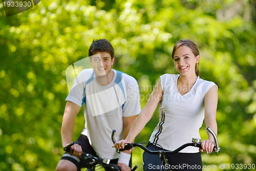 Image of Happy couple riding bicycle outdoors