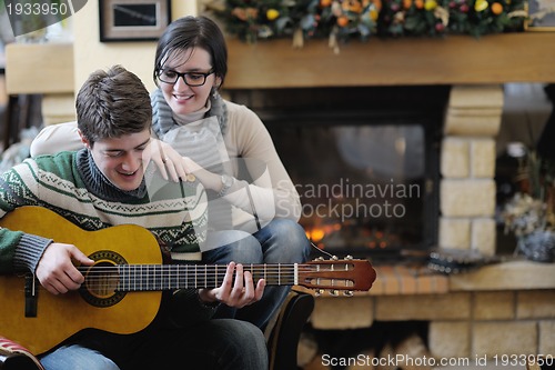 Image of Young romantic couple sitting and relaxing in front of fireplace