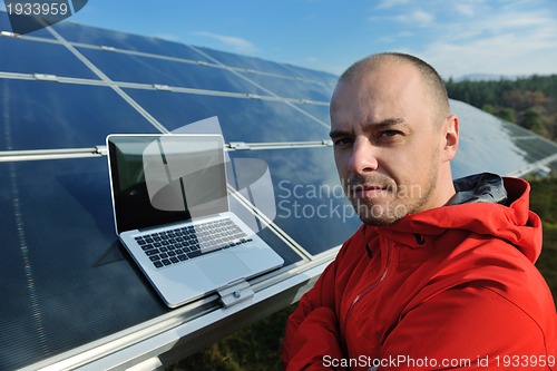 Image of engineer using laptop at solar panels plant field