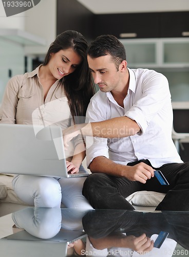 Image of joyful couple relax and work on laptop computer at modern home