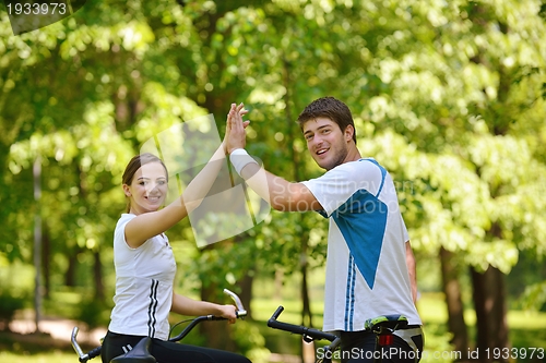 Image of Happy couple riding bicycle outdoors