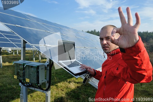 Image of engineer using laptop at solar panels plant field